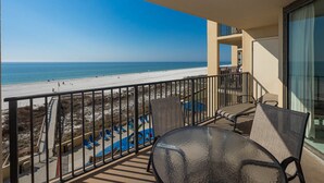 Ein Balkon mit Blick auf den Strand, Liegestühlen und einem Poolbereich.