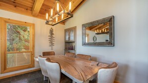 A dining area with a wooden table and chairs, a chandelier, a large mirror, and a window with a view of trees. - Clearview 2 - Amazing Tahoe Views, Dog Friendly, Pool Table, Near Golf (Tahoe City)