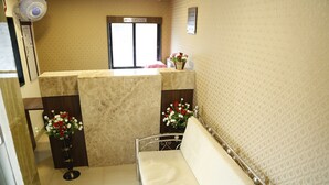 A reception area with a reception desk, a sofa, and two flower arrangements. - Hotel Royal Onix Mumbai (Mumbai)