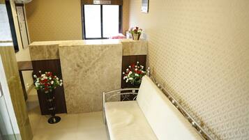 A reception area with a reception desk, a sofa, and two flower arrangements.