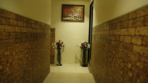 A hallway with brick walls, two vases with flowers, and a painting of the Taj Mahal on the wall. - Hotel Royal Onix Mumbai (Mumbai)