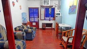 A family room with a sofa, chairs, a table, and a television. - Rositas Hotel (San Juan del Sur)