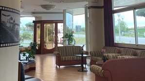 Eine großzügige Lobby mit hoher Decke, eingelassener Beleuchtung und großen Fenstern mit Blick ins Freie.