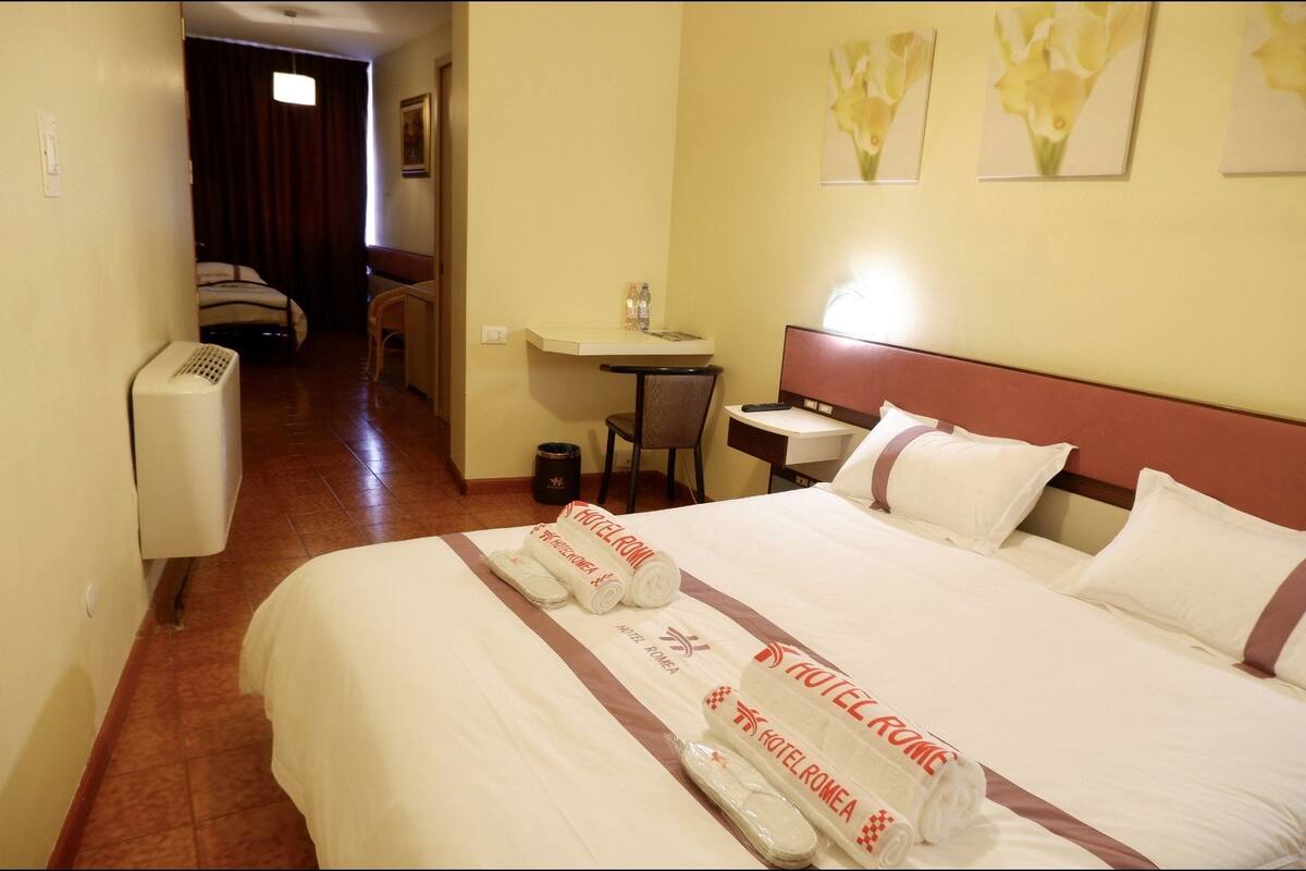 Ein Hotelzimmer mit einem großen Bett, einem Schreibtisch, einem Stuhl und einem kleinen Tisch.