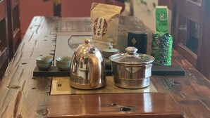 Ein Holztisch mit Teekanne, Tasse und einer Packung Tee.