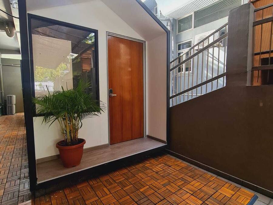 Una habitación moderna y compacta con puerta de madera, una planta en maceta y suelo con motivo de espiga.
