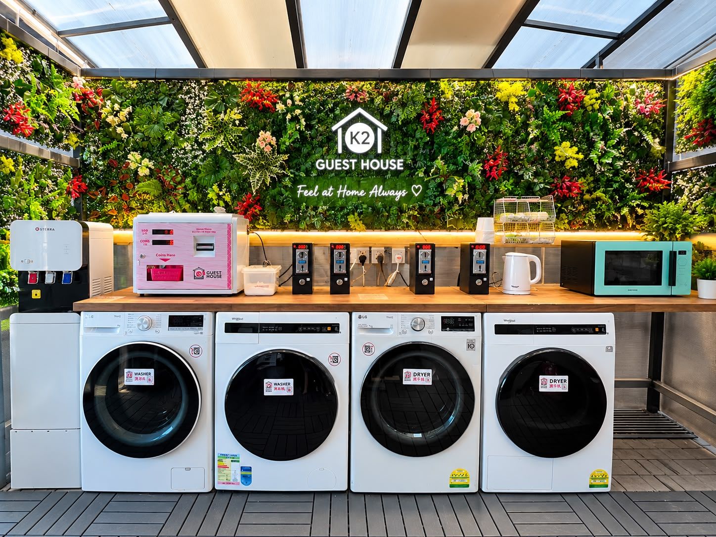 Zona de lavandería automática con varias lavadoras, secadoras, una máquina de café con monedas y un microondas.