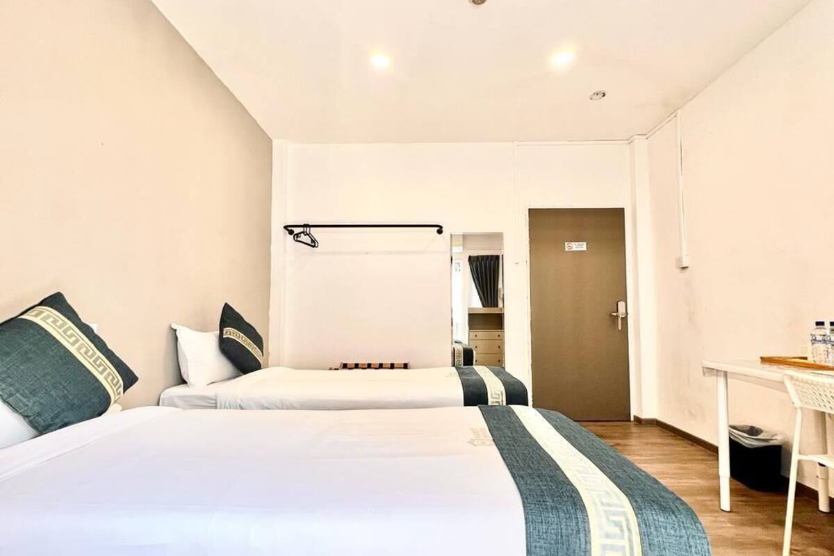 A hotel room with two beds, a desk, and a wardrobe.
