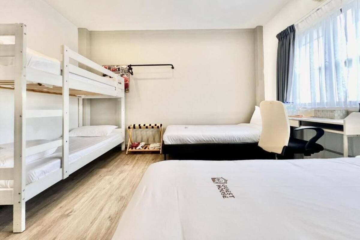 A hotel room with bunk beds, a desk, and a chair.