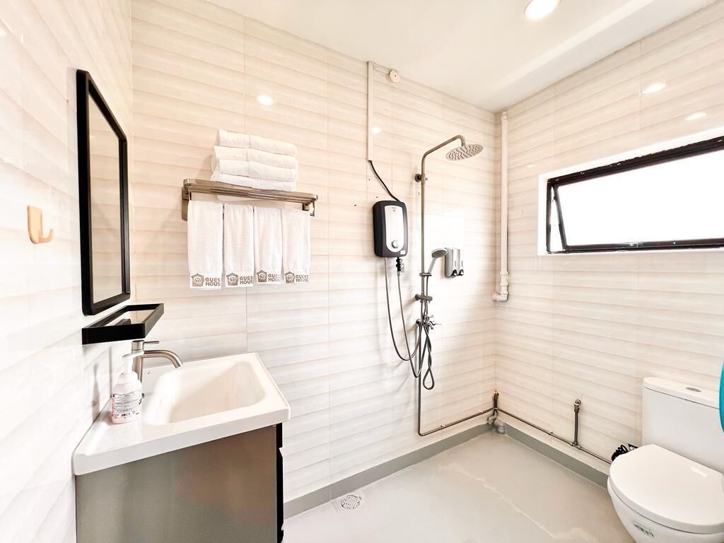 A modern bathroom with a sink, mirror, towel rack, shower, and toilet.