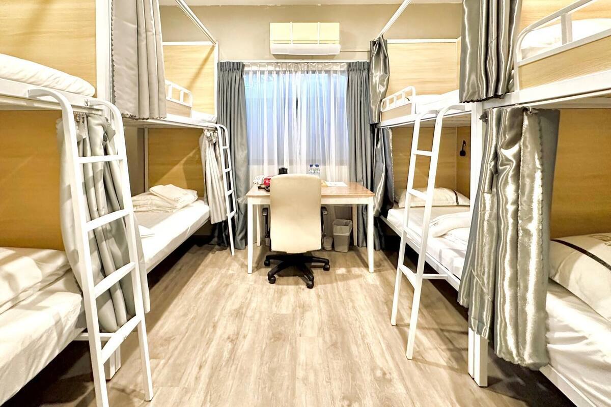 A room with three bunk beds, a desk, and a chair.