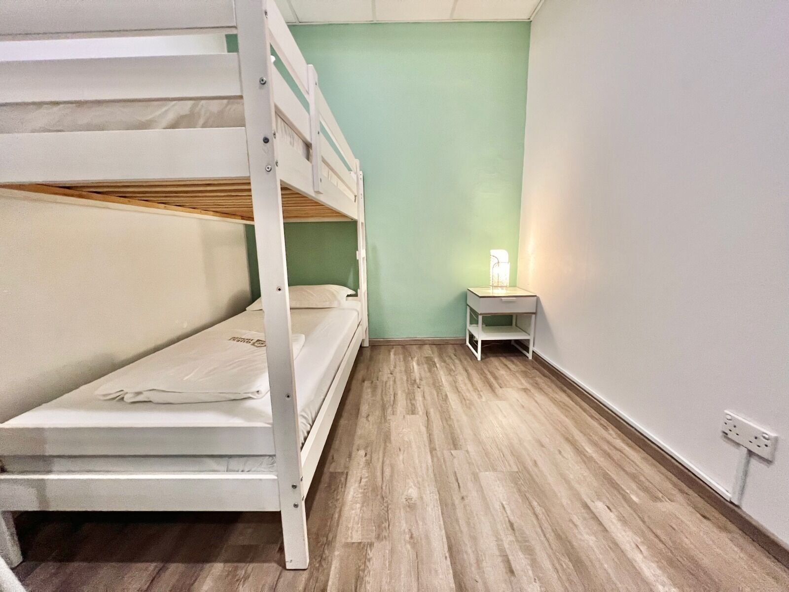 A bunk bed room with a nightstand and a lamp.