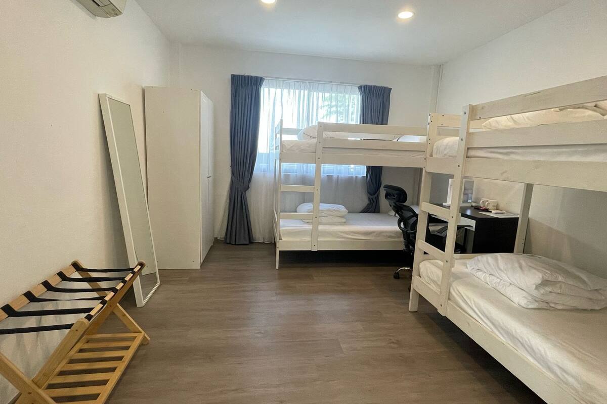 A bunk bed room with a desk and chair, a wooden ladder, and a door.