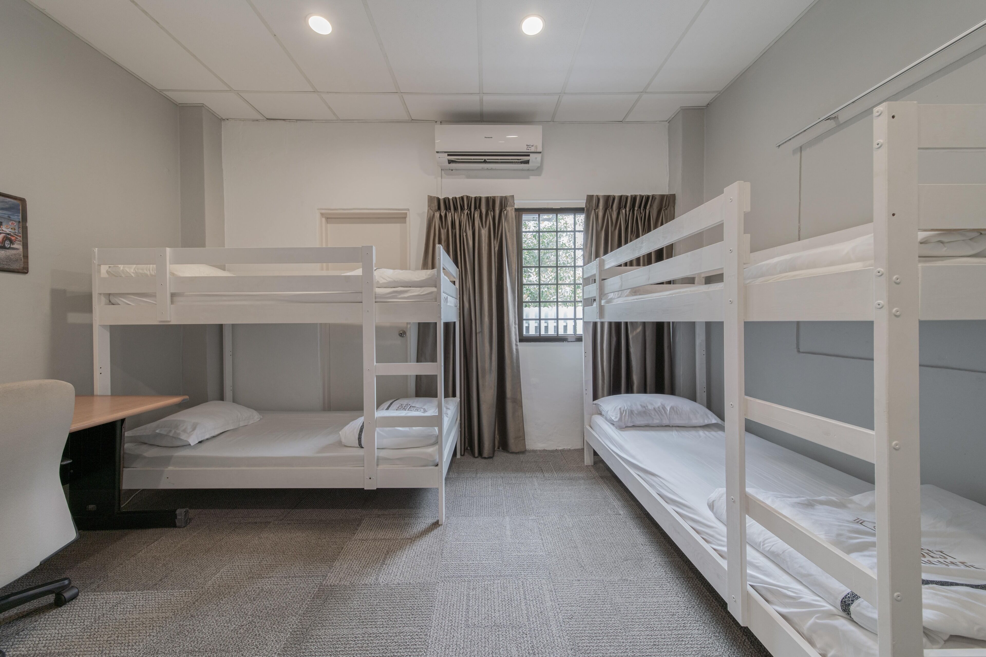A room with bunk beds, a desk, and a window with curtains.