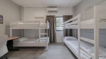 A room with bunk beds, a desk, and a window with curtains.
