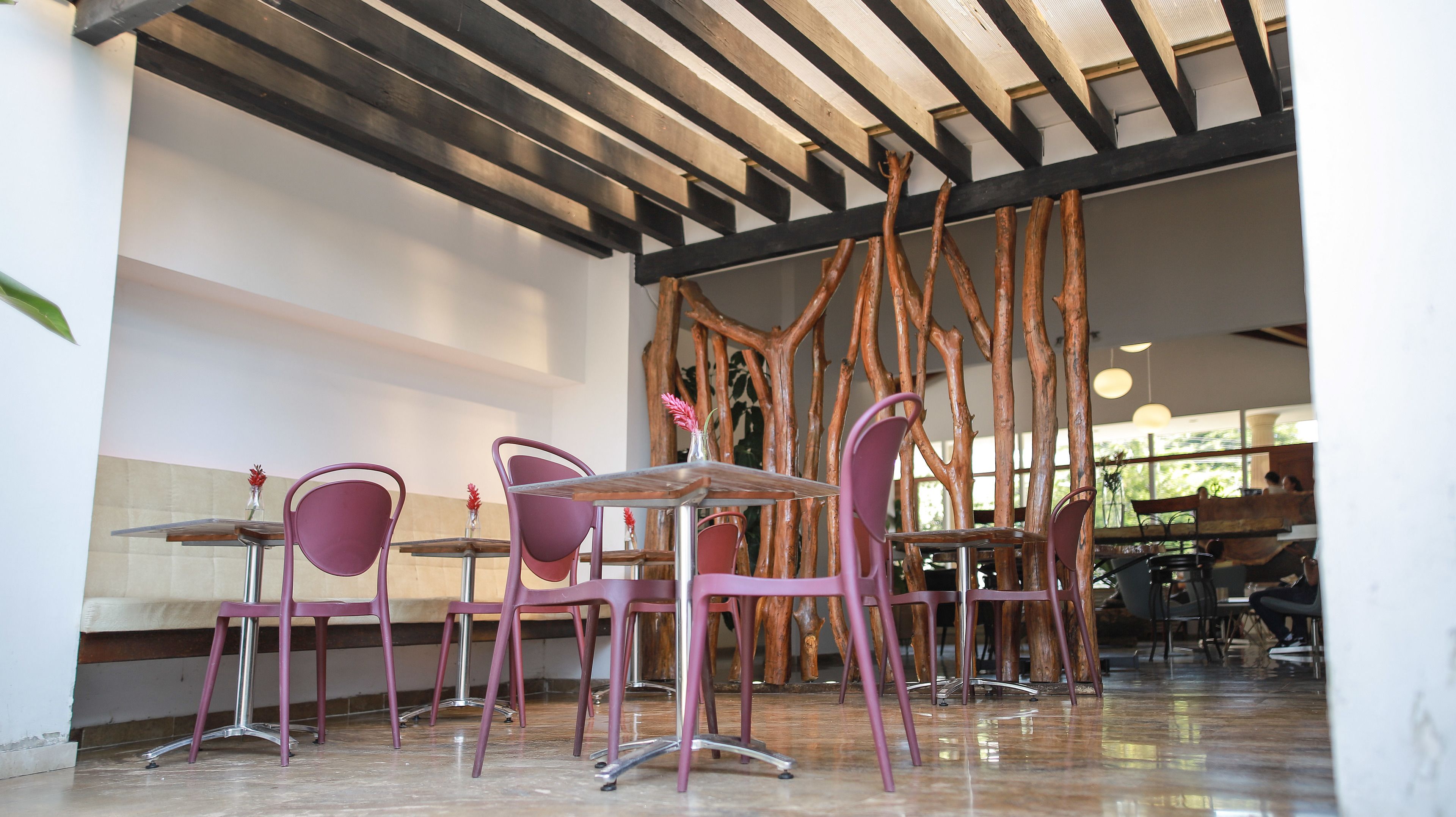 Interior de restaurante con diseño moderno, que presenta un techo de madera, una mesa central con sillas y una pared decorativa de madera.