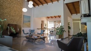 A spacious living area with a high ceiling, modern furniture, and a stone wall. - Royal Garden Hotel Boutique (Cali)