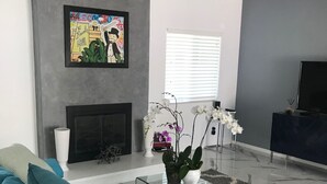 A modern living room with a blue sofa, a fireplace, a flat-screen TV, and a framed artwork on the wall. - The Colony House Palm Springs (Palm Springs)