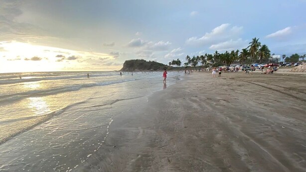 A beach with a clear sky and calm sea, palm trees, and people in the distance. - Condo Musta 2 (Cancun)