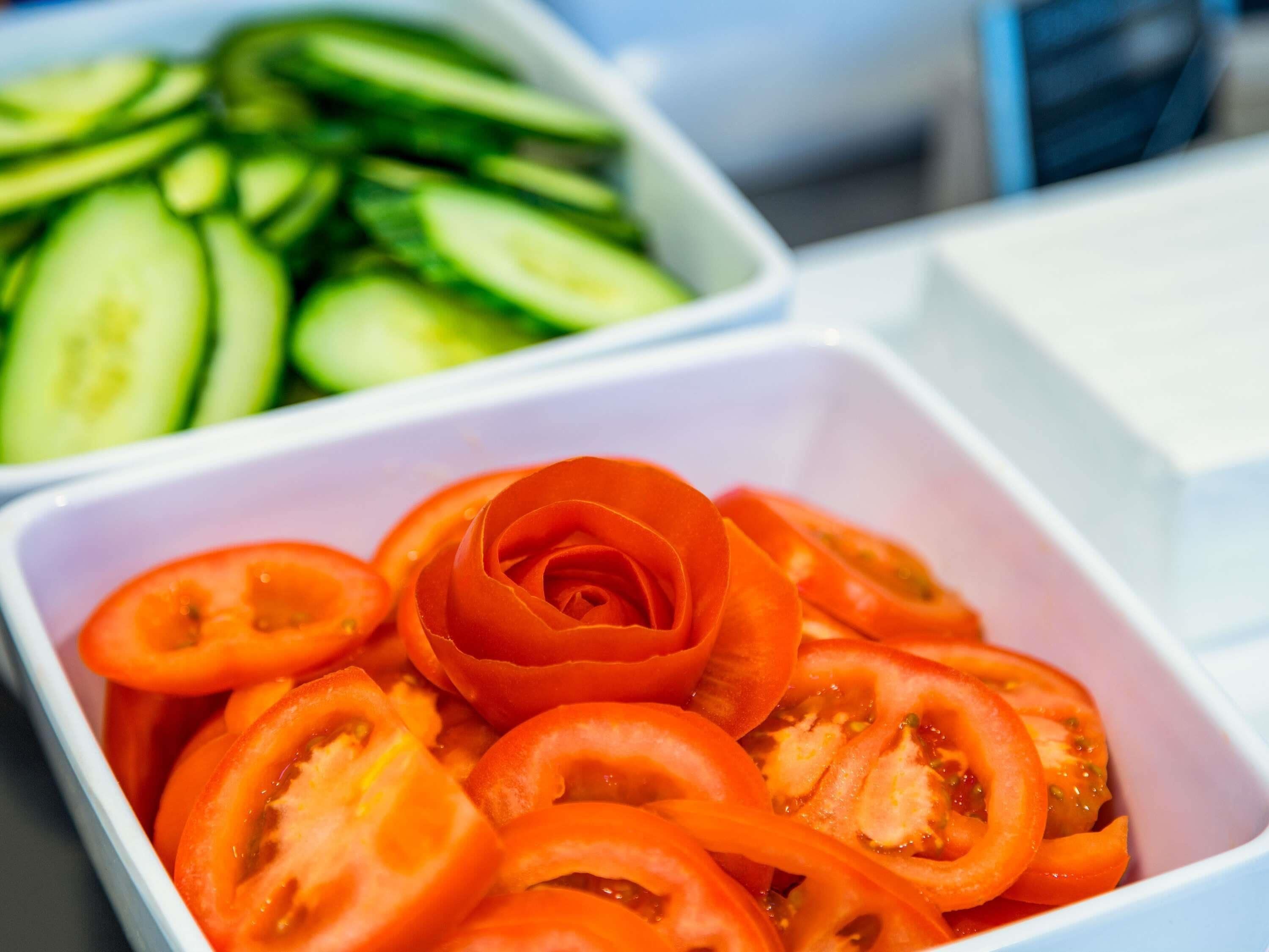 Dos recipientes blancos rectangulares, uno con rodajas de tomate y otro con rodajas de pepino.