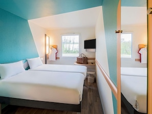 Una habitación de hotel con dos camas, televisión, ventana y baño.