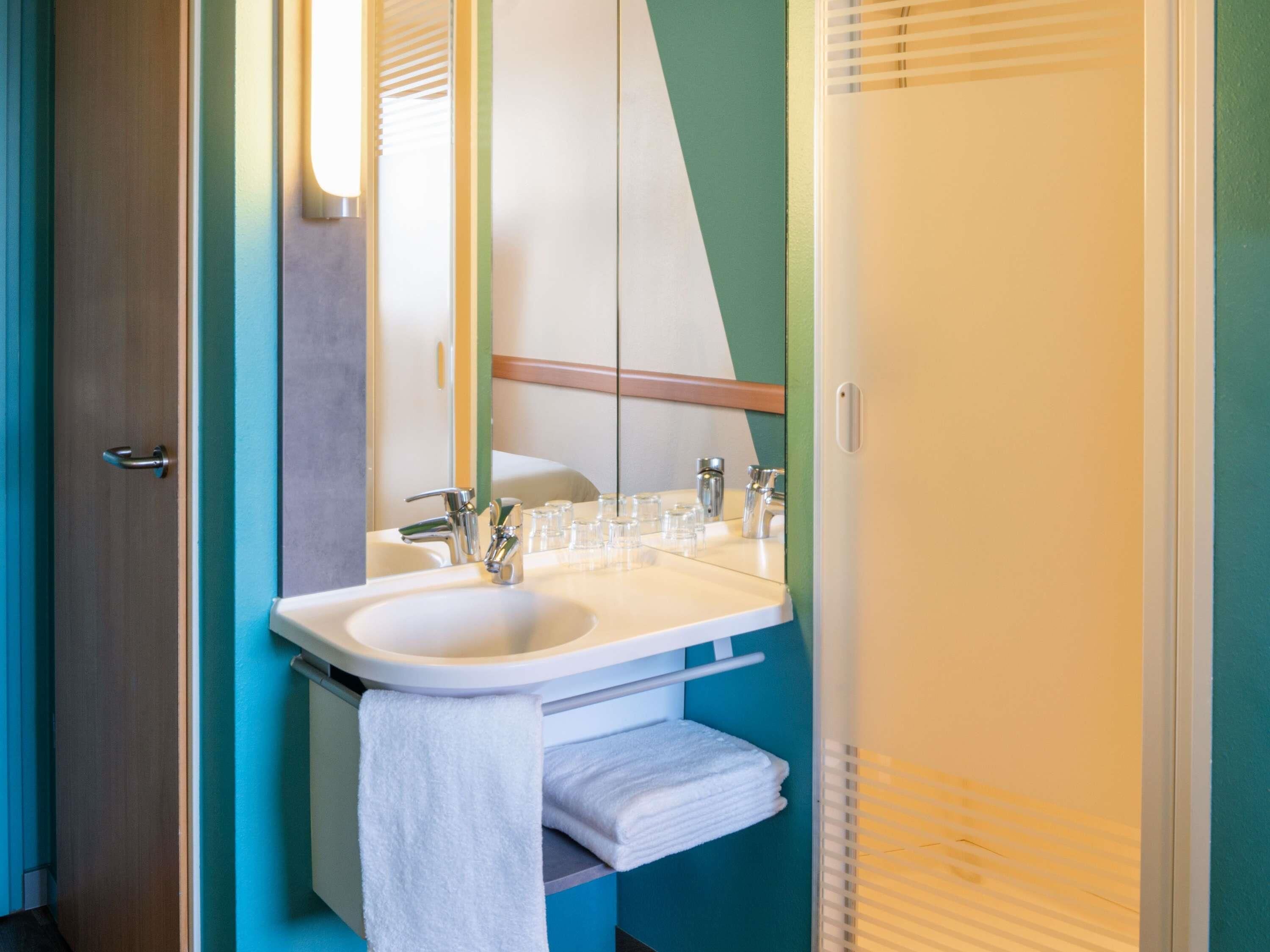 A bathroom with a sink, mirror, towel rack, and a door.