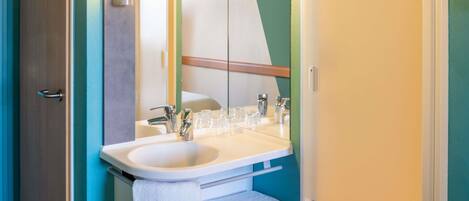 A bathroom with a sink, mirror, towel rack, and a door.