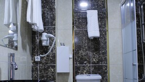 A bathroom with a black sink, white toilet, and a glass shower enclosure. - Sinan Hotel (Ankara)