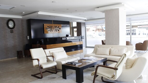 A modern reception area with a reception desk, two sofas, and a coffee table. - Sinan Hotel (Ankara)