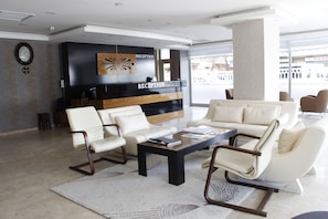 A modern reception area with a reception desk, two sofas, and a coffee table. - Sinan Hotel (Ankara)