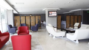 A modern lobby with red and white seating, a television, and traditional decor. - Sinan Hotel (Ankara)