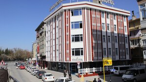 A hotel with a red and white facade, multiple windows, and a sign indicating it is a hotel. - Sinan Hotel (Ankara)