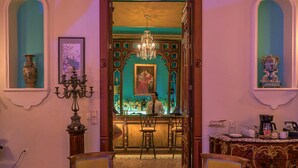 A lobby with a bar area, two armchairs, a chandelier, and a patterned floor. - El Palacito Secreto (Mérida)