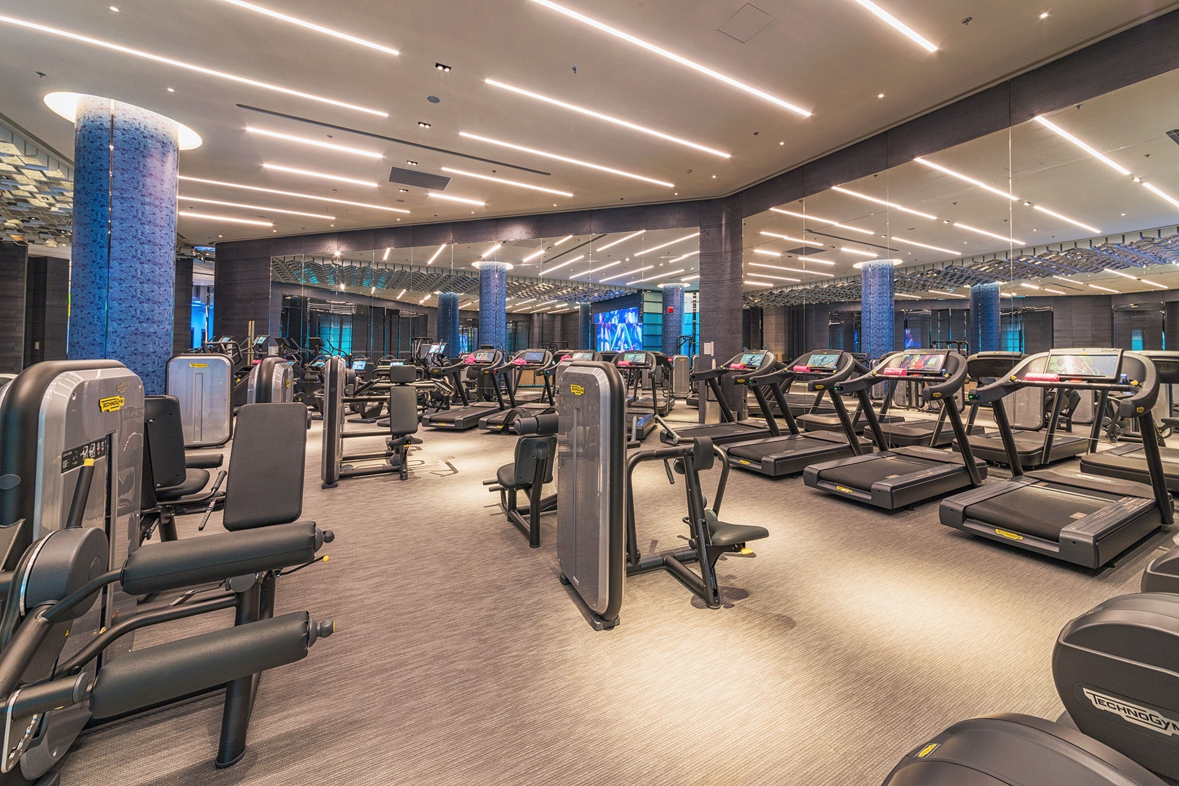 A modern gym with multiple treadmills, weight machines, and a spacious layout.