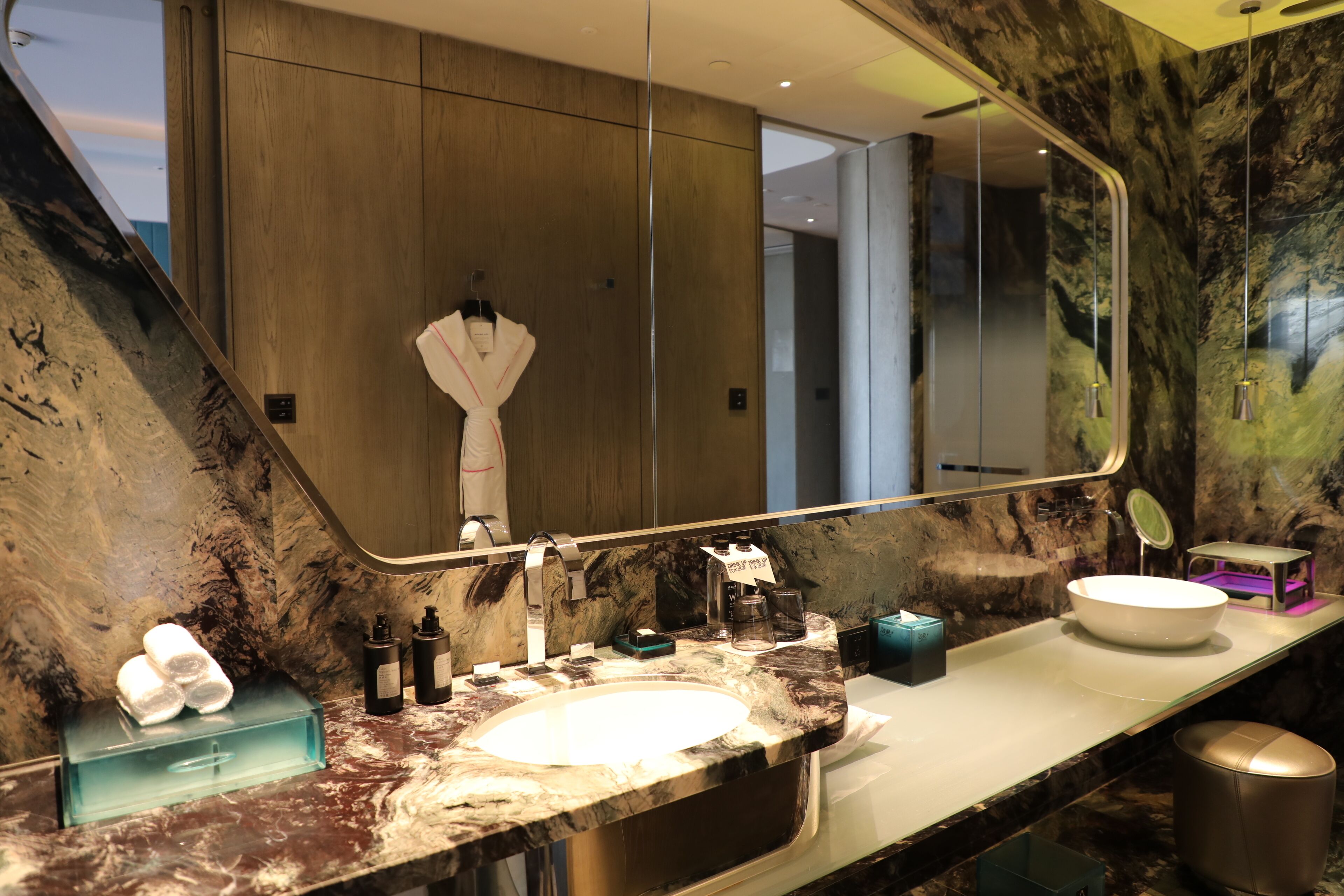 A modern bathroom with a large mirror, marble countertop, and a white sink.