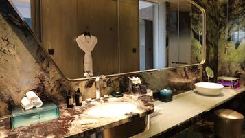 A modern bathroom with a large mirror, marble countertop, and a white sink.
