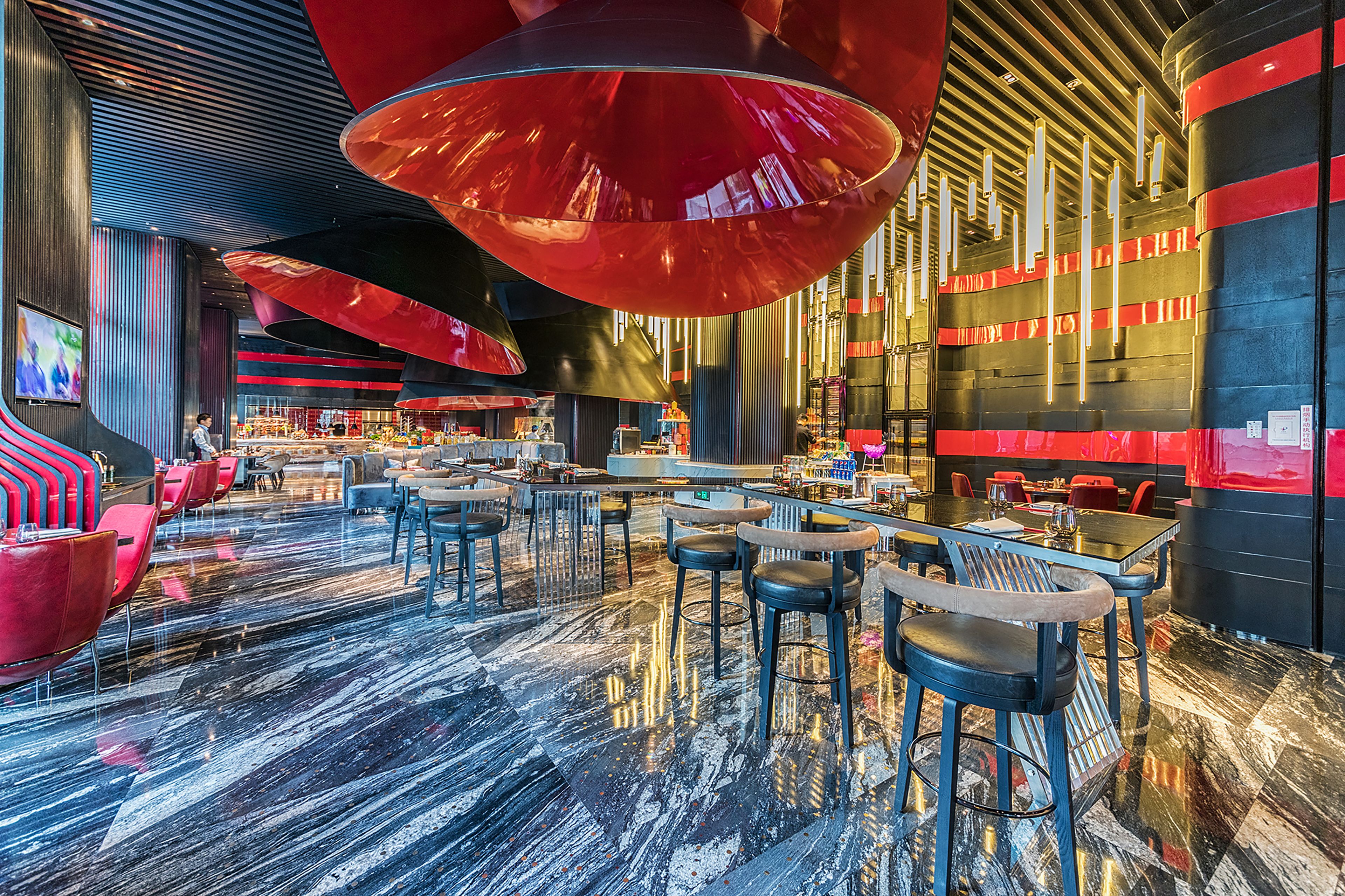Un restaurante moderno con suelo de mármol pulido, decoración en rojo y negro, e iluminación contemporánea.