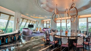 A modern dining area with a round table, chairs, and a city view.