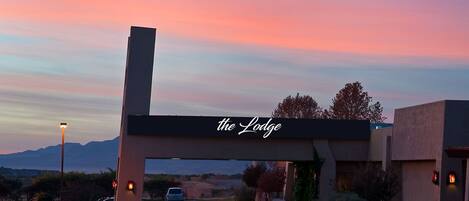 A hotel entrance with a sign reading "the Lodge" against a sunset sky.