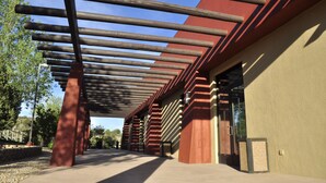 Une galerie couverte à l’architecture moderne, caractérisée par une série de poutres en bois et d’éléments structurels rouges.
