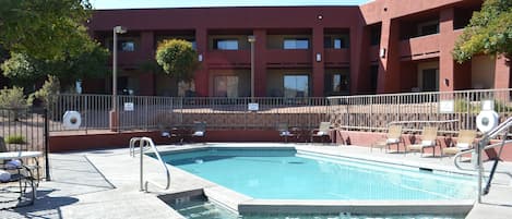 Une piscine avec des chaises longues et un bâtiment en arrière-plan.