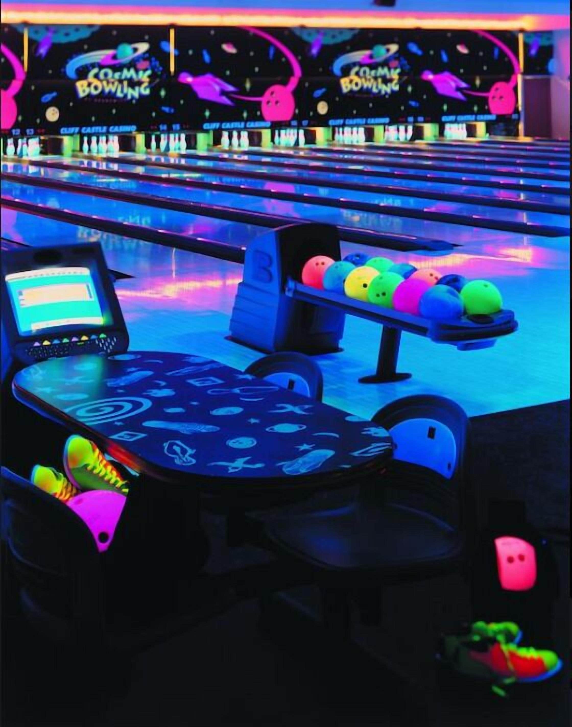 En bowlinghal med neonskilte og et område til at returnere bowlingkugler.