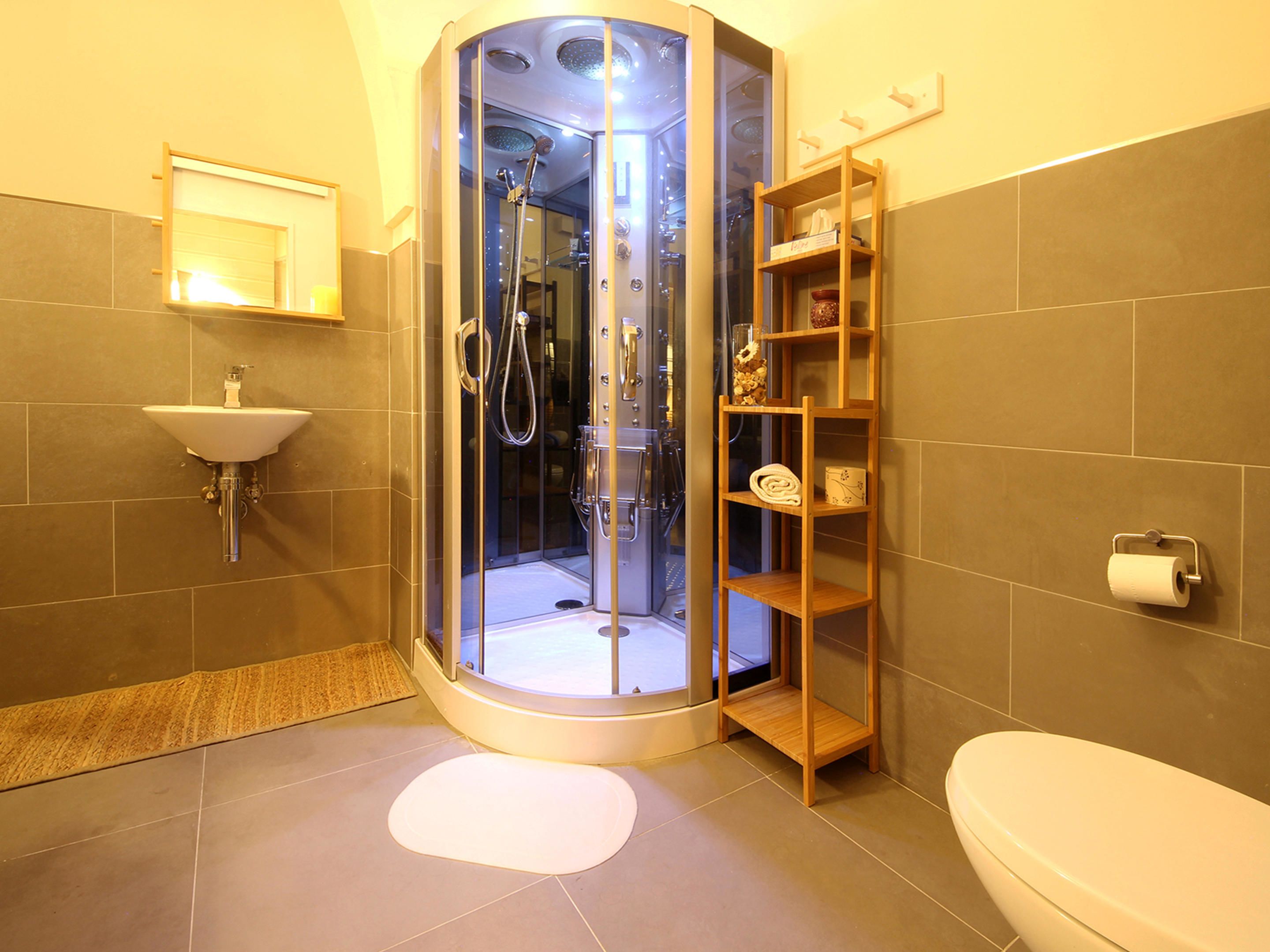 A modern bathroom with a glass-enclosed shower, a sink, and a toilet.