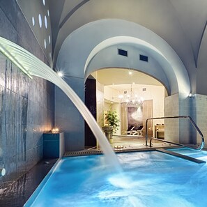 A modern indoor pool with a water feature, arched ceilings, and a reception area visible through an archway. - Dimora Nettare (Brindisi)