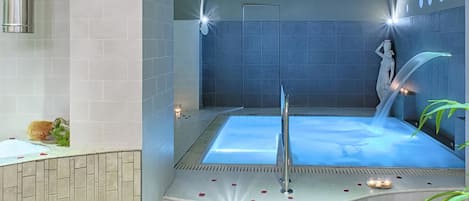 Un spa moderne doté d’un grand jacuzzi, d’une statue et d’un mur décoratif orné de motifs circulaires.