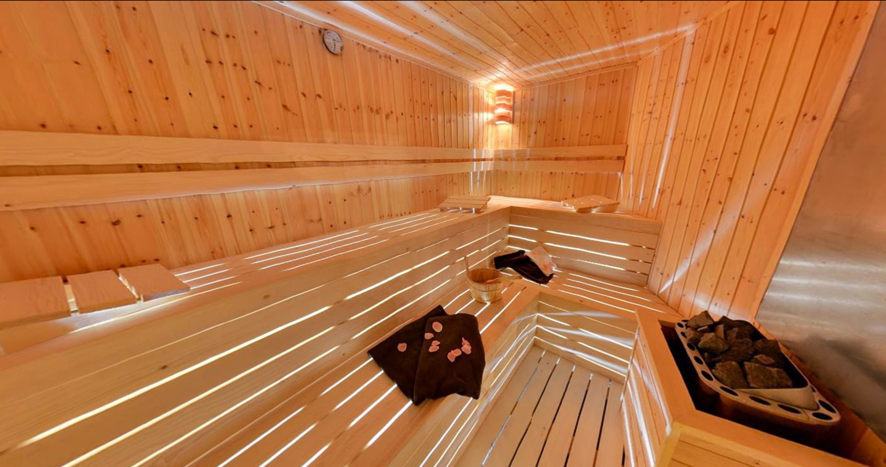 Sauna amb bancs de fusta, un escalfador i un suport per a tovalloles.