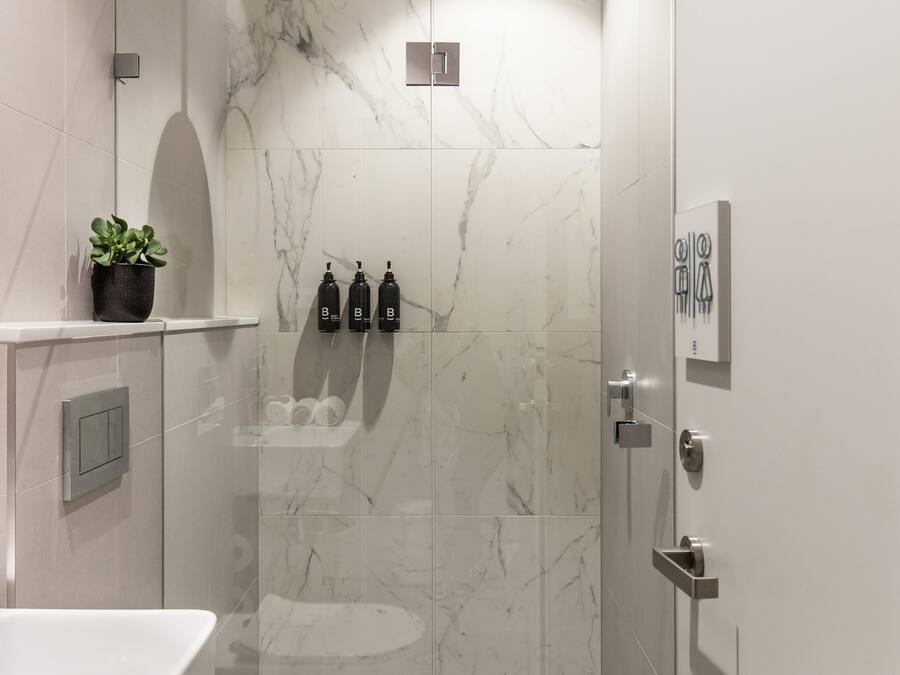Ein modernes Badezimmer mit einer Duschkabine aus Glas, einer weißen Toilette und einer Marmor-Spritzschutzwand.