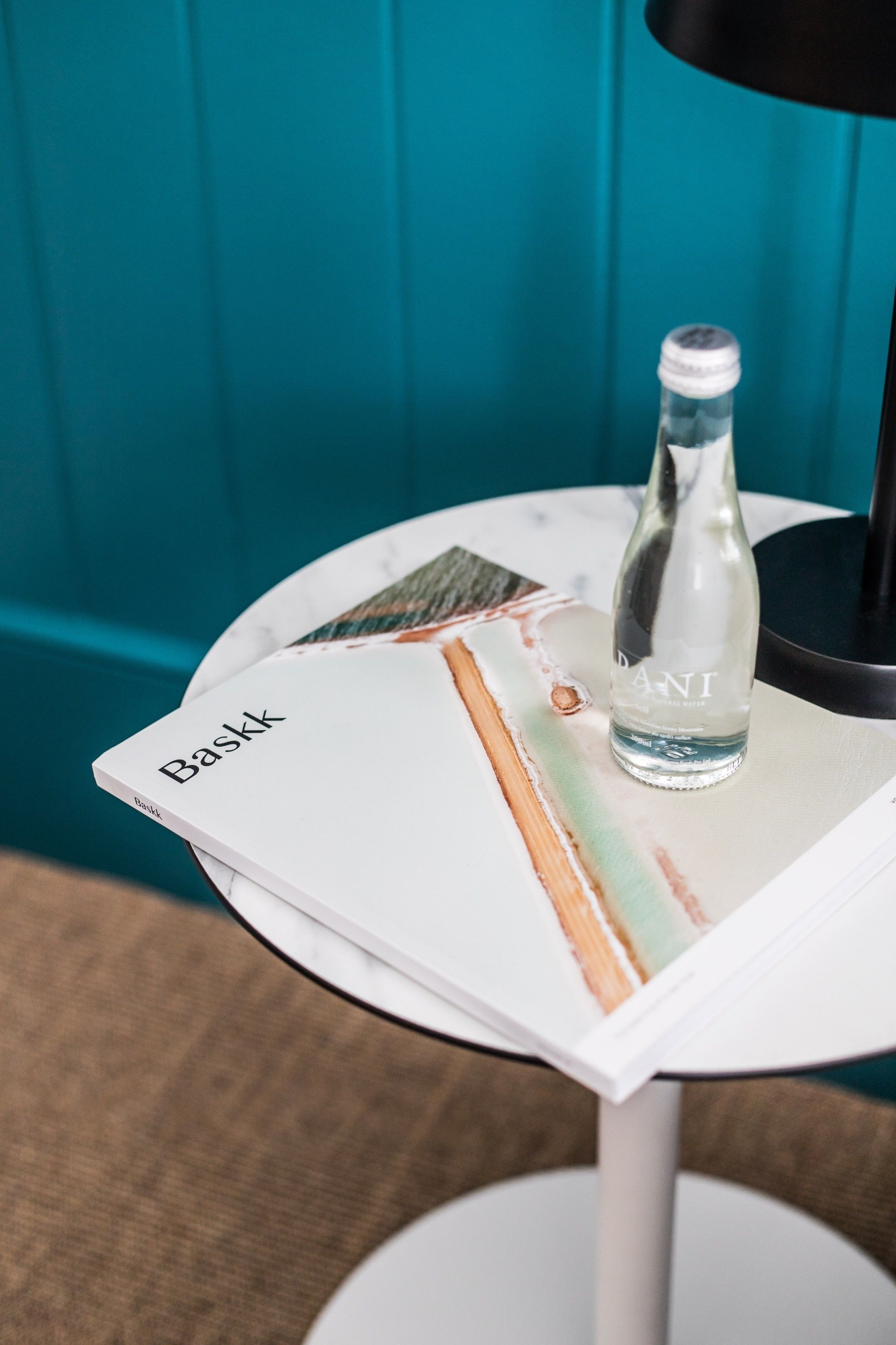 A bottle of water on a table with a magazine.