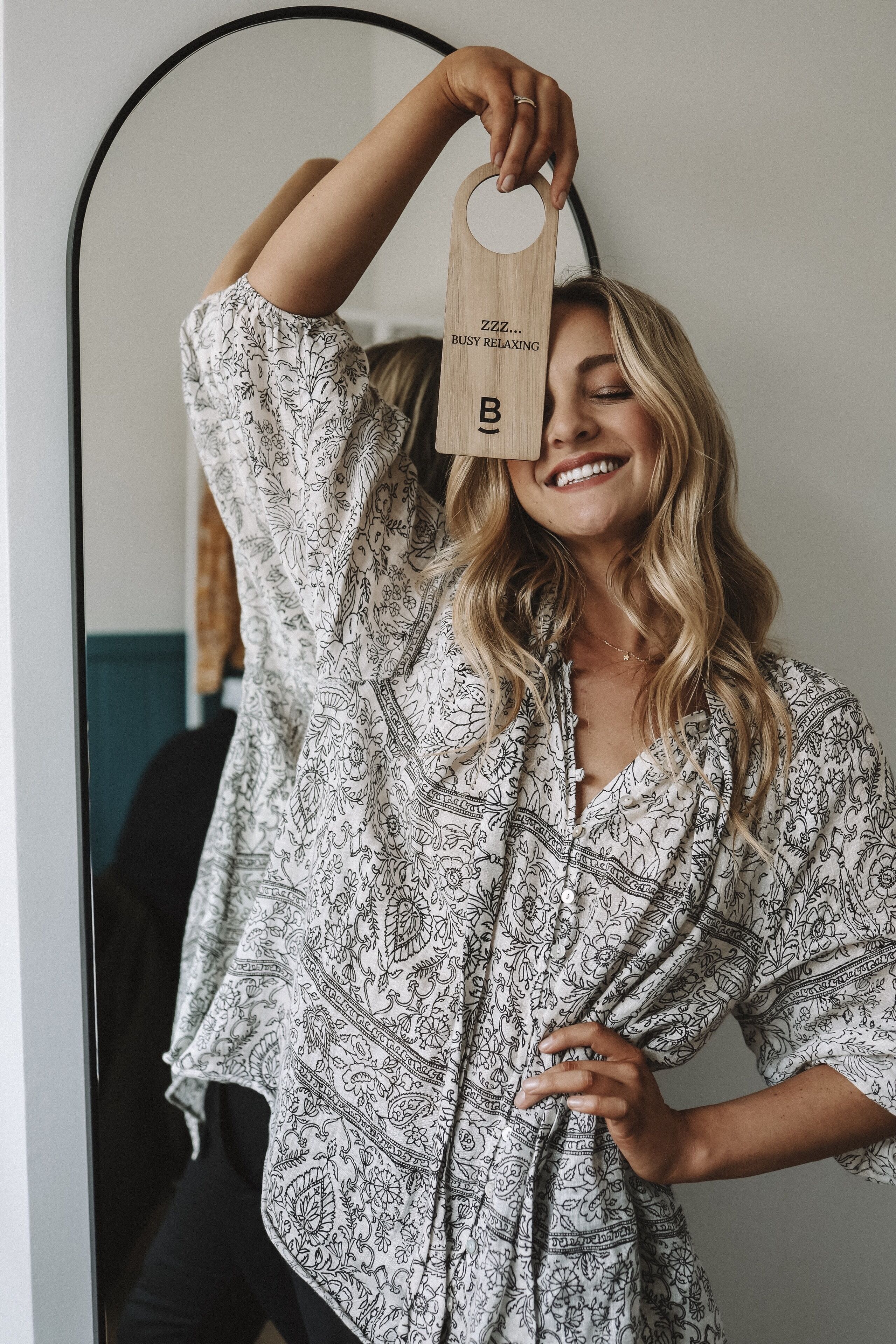 Une personne portant une chemise à motifs, debout devant un miroir.