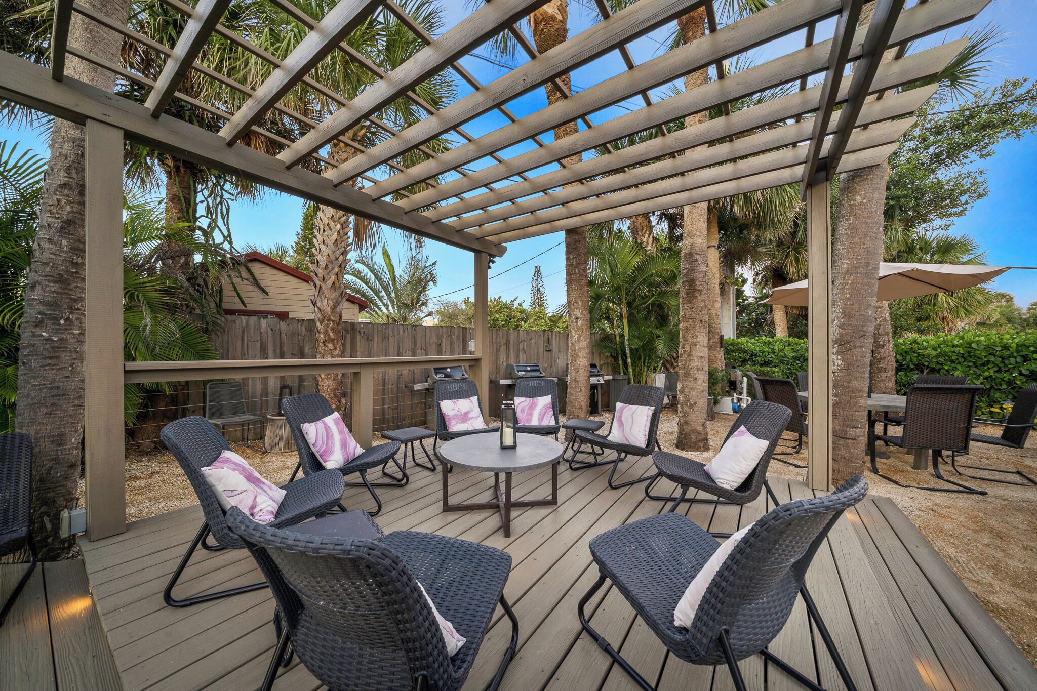 An outdoor patio with wicker furniture and a pergola.